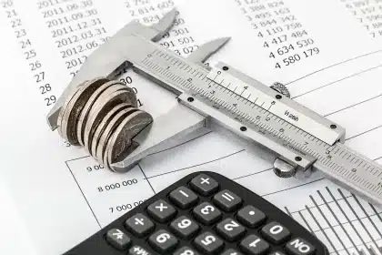 Main posant des factures et une calculatrice sur une table de cuisine en plein jour