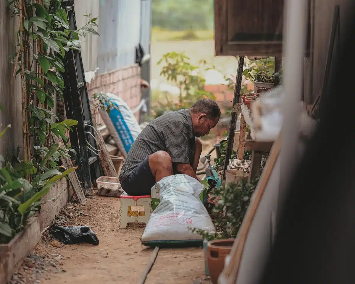 Main gantée manipulant une motobineuse sur un potager en plein jour