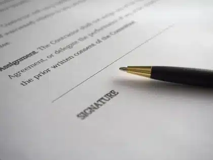 Personne signant un document juridique à un bureau en plein jour