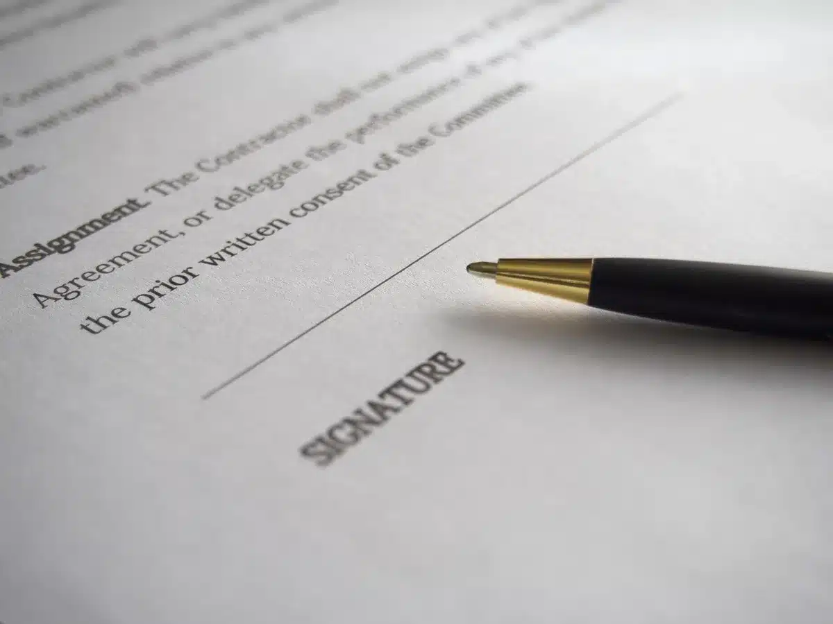 Personne signant un document juridique à un bureau en plein jour